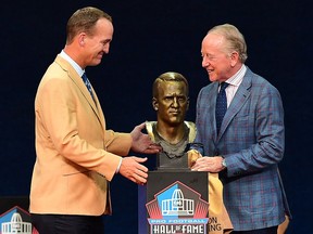 Peyton Manning (left) unveils his bust with his father Archie Manning during the Hall of Fame Enshrinement Ceremony at Tom Benson Hall Of Fame Stadium on August 8, 2021 in Canton, Ohio.