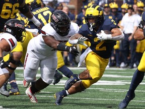 Blake Corum of the Michigan Wolverines tries to get around the tackle of Nick Rattin and James Ester of the Northern Illinois Huskies during a first half run at Michigan Stadium on September 18, 2021 in Ann Arbor, Michigan.
