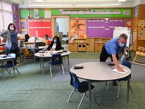 A man sanitizes tabletop surfaces in a Kindergarten classroom at Hunter's Glen Junior Public School in Scarborough on Sept. 14, 2020.