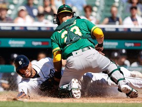Oakland Athletics' catcher Yan Gomes (23) tags out Detroit Tigers outfielder Victor Reyes (22) at home in the third inning at Comerica Park on Thursday.