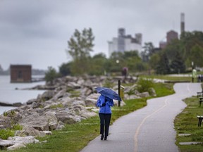 WINDSOR, ONTARIO:. SEPTEMBER 23, 2021 - Rain continued to fall as a woman walks along a quiet riverfront on Thursday, Sept. 23, 2021.
