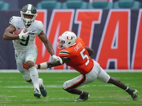 Michigan State Spartans running back Kenneth Walker III runs the ball past Miami Hurricanes safety Amari Carter during the second half at Hard Rock Stadium.