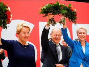 Social Democratic Party (SPD) top candidate for chancellor Olaf Scholz, Mecklenburg-Western Pomerania state Prime Minister Manuela Schwesig and SPD member Franziska Giffey hold up bouquets of flowers at their party leadership meeting, one day after the German general elections, in Berlin, Germany, Sept. 27, 2021.
