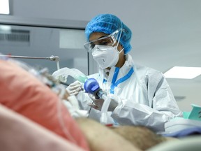 FILE: A nurse treats a patient with COVID-19 in an ICU.