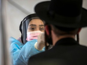 A health-care worker takes a swab sample from an Ultra-Orthodox Jewish man for the COVID-19 test, after returning from overseas, at Ben Gurion International Airport in Lod, near Tel Aviv, Israel April 13, 2021.