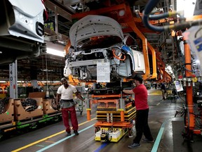 FILE PHOTO: General Motors assembly workers connect a battery pack underneath a partially assembled 2018 Chevrolet Bolt EV vehicle on the assembly line at Orion Assembly in Lake Orion, Michigan, U.S., March 19, 2018.