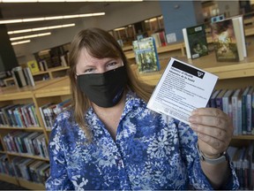 Sue Perry, team leader at the Windsor Public Library, holds a recently laminated vaccine passport at the downtown branch, a service the Windsor Public Library is providing free of charge, on Tuesday, Sept. 28, 2021.