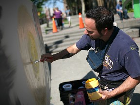 Jay Raven, a Windsor artist, works on a painting in the downtown area in this 2014 file photo.