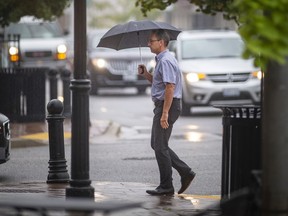 A pedestrian shields himself from a light drizzle as he walks along Wyandotte Street East in Walkerville, on Tuesday, Sept. 21, 2021.  A rainfall warning has been issued by Environment Canada for Windsor-Essex.