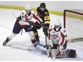 Windsor Spitfires' rookie goalie Kyle Downey makes a stop as teammate James Jodoin battles Noah Nelson of the Hamilton Bulldogs on Sunday at the WFCU Centre.