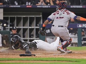 Luis Robert of the Chicago White Sox slides in to score a run as the ball gets away from Martin Maldonado of the Houston Astros at Guaranteed Rate Field on October 10, 2021 in Chicago, Illinois. The White Sox defeated the Astros 12-6.