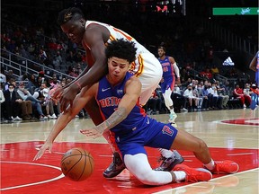 Killian Hayes of the Detroit Pistons battles for a loose ball against Clint Capela of the Atlanta Hawks during the first half at State Farm Arena on October 25, 2021 in Atlanta, Georgia.