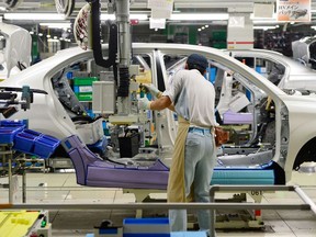 A Toyota Motor employee fixes the main battery of the hybrid system on an assembly line for the Corolla Axio at a plant of the company's subsidiary Toyota Motor East Japan in the village of Ohira, Miyagi prefecture, northern Japan, on August 23, 2013. The new hybrid Corolla, equipped with a 1.5-litre gasoline engine and an electric motor, claims to achieve a mileage of 33 kms per litre.