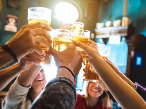 Group of happy friends drinking and toasting beer at brewery bar restaurant.