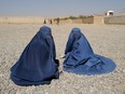 Displaced Afghan women wait to receive aid supply from UNHCR agency outside the distribution center on the outskirts of Kabul, Afghanistan, Oct. 28, 2021.