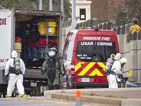 A man in an explosive disposal suit and the Windsor Fire and Rescue hazmat unit work at the Ambassador Bridge after possible explosives were discovered in a vehicle entering into Canada, on Monday, Oct. 4, 2021.