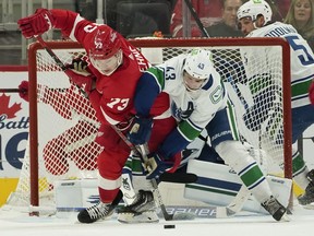 Detroit Red Wings left wing Adam Erne and Vancouver Canucks defenseman Quinn Hughes battle for the puck in the second period of an NHL hockey game Saturday, Oct. 16, 2021, in Detroit.