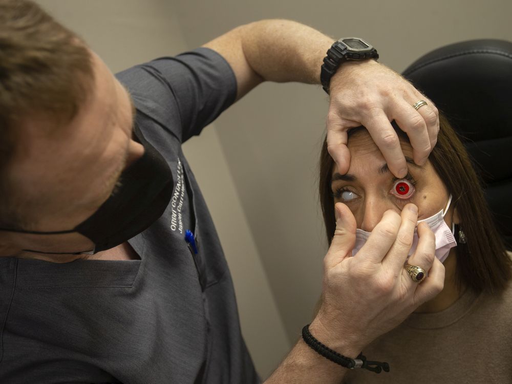 Jason Carruthers, an optician, places a costume contact lens on assistant Mariana Carruthers, at Orbit Contact Lens on Thursday, Oct. 28, 2021.