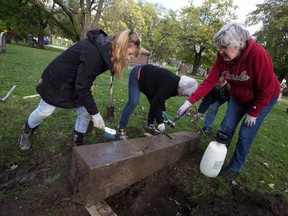 C. J. Scott (left), Rosemary Lunau, Marty LeBlanc and Pat Clancy (right), all members of the Ontario Genealogical Society's Essex County Branch, wash off an unearthed monument pillar in search of a name at Windsor Grove Cemetery on Tuesday, Oct. 26, 2021.