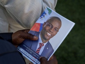 A person holds a photo of late Haitian President Jovenel Moise, who was shot dead earlier this month, during his funeral at his family home in Cap-Haitien, Haiti, July 23, 2021.