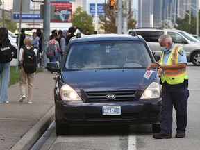 A parking enforcement officer issues a ticket near W. C. Kennedy Collegiate secondary school in Windsor on Oct. 8, 2021.
