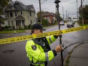 Police officers with the accident reconstruction unit investigate at the intersection of Janette Avenue and Elliott Street West after a male was found with life-threatening injuries, on Friday, Oct. 15, 2021.