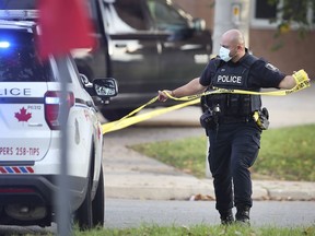 A Windsor officer puts up police tape at the scene of a possible assault on Sunday, Oct. 3, 2021, in the 300 block of Elliott Street West.