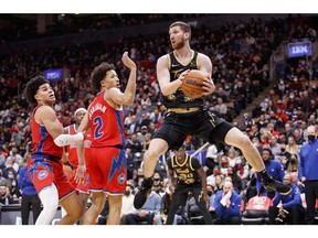 Svi Mykhailiuk #14 of the Toronto Raptors looks to make a pass as Cade Cunningham #2 and Killian Hayes #7 of the Detroit Pistons defend during the second half of their NBA game at Scotiabank Arena on November 13, 2021 in Toronto, Canada.
