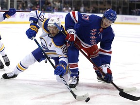 Zemgus Girgensons of the Buffalo Sabres and Kevin Rooney of the New York Rangers fight for the face off in the first period at Madison Square Garden on November 21, 2021 in New York City.