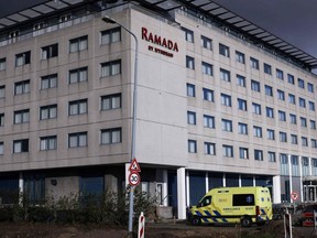 This photo taken Monday, Nov. 29, 2021 in Badhoevedorp near Schiphol airport, shows an an ambulance parked in front of a hotel where Dutch authorities have isolated 61 passengers who tested positive after arriving on two flights from South Africa.