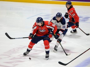 Windsor Spitfires' forward Matthew Maggio tries to control the puck while fending off Saginaw Spirit defenceman Pavel Mintyukov while Windsor teammate Oliver Peer looks on during Saturday's game.