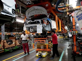 FILE PHOTO: General Motors assembly workers connect a battery pack underneath a partially assembled 2018 Chevrolet Bolt EV vehicle on the assembly line at Orion Assembly in Lake Orion, Michigan, U.S., March 19, 2018.