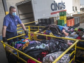 Paul Kane with Cintas, helps deliver large bins of used coats the company has cleaned and delivered to the UHC-Hub of Opportunities for the organization's Coats for Kids campaign, on Wednesday, Nov. 24, 2021.