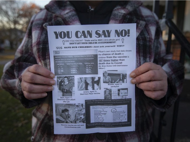  Bronwyn Greenacre holds an anti-vaccine flyer she received outside her children’s school, on Tuesday, Nov. 23, 2021.