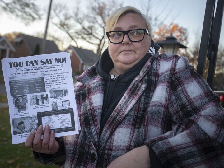  Bronwyn Greenacre holds an anti-vaccine flyer she received outside her children’s school, on Tuesday, Nov. 23, 2021.