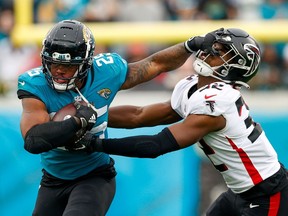 Nov 28, 2021; Jacksonville, Florida, USA;  Jacksonville Jaguars running back James Robinson (25) holds off Atlanta Falcons safety Jaylinn Hawkins (32) in the second half at TIAA Bank Field. Mandatory Credit: Nathan Ray Seebeck-USA TODAY Sports     TPX IMAGES OF THE DAY