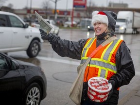 Janette Vlieger, with the Canadian Motorcycle Cruisers - Windsor Chapter, hands out editions of the Goodfellows newspaper at the intersection of Howard Avenue and Tecumseh Road East, on Thursday, Nov. 25, 2021.