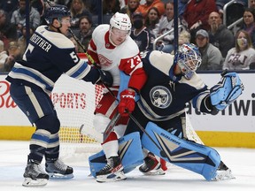 Columbus Blue Jackets goalie Elvis Merzlikins makes a save as Detroit Red Wings left wing Adam Erne collides with him during the second period at Nationwide Arena.