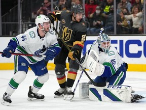 Vancouver Canucks goaltender Thatcher Demko (35) defends his net as defenseman Kyle Burroughs (44) covers Vegas Golden Knights center Brett Howden (21) during the second period at T-Mobile Arena.