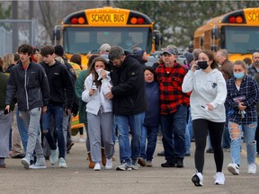 Parents walk away with their kids from the Meijer's parking lot where many students gathered following an active shooter situation at Oxford High School in Oxford, Michigan, U.S. November 30, 2021.
