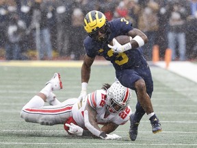 Michigan Wolverines wide receiver A.J. Henning rush the ball passed Ohio State Buckeyes linebacker Steele Chambers in the first half at Michigan Stadium.