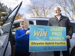 Kathleen Stasso and Mayor Drew Dilkens pose for a photo after Stasso was presented with her new 2021 Chrysler Pacifica Hybrid she won through the WEVax to Win lottery, on Monday, Nov. 22, 2021.