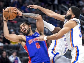 Trey Lyle of the Detroit Pistons grabs a rebound against Luguentz Dort and Kenrich Williams of the Oklahoma City Thunder during the fourth quarter at Little Caesars Arena on December 06, 2021 in Detroit, Michigan.