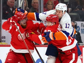 Matt Martin of the New York Islanders tries to skate trough Gustav Lindstrom and Marc Staal of the Detroit Red Wings during the first period at Little Caesars Arena on December 04, 2021 in Detroit, Michigan.