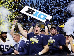 INDIANAPOLIS, INDIANA - DECEMBER 04: Aidan Hutchinson #97 of the Michigan Wolverines celebrates with the trophy after the Michigan Wolverines beat the Iowa Hawkeyes 42-3 to win the Big Ten Championship game at Lucas Oil Stadium on December 04, 2021 in Indianapolis, Indiana.