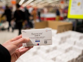 Customers look at COVID-19 rapid test kits sold in a supermarket in Saint-Herblain, France, Wednesday, Dec. 29, 2021.