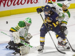 Knights goaltender Brett Brochu watches a deflected puck after making a stick save with Carey Terrance of the Erie Otters camped in front of the Knights net while being checked by Isaiah George during a game Friday, Oct. 3, 2021 at Budweiser Gardens in London. Brochu made 32 saves in the Knights' 4-1 win. (Mike Hensen/The London Free Press)