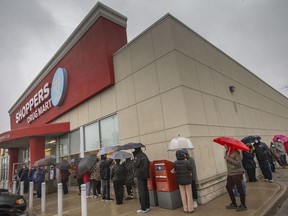 Customers line up for a vaccine clinic at a Shoppers Drug Mart location in Amherstburg, Ontario, on Dec. 18, 2021.