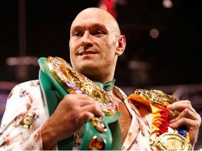 Tyson Fury poses with his belts during a press conference after the fight