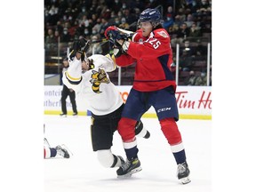 Windsor Spitfires' forward Kyle McDonald, at right, knocks down Sarnia Sting's Theo Hill in the first period of Friday's game.